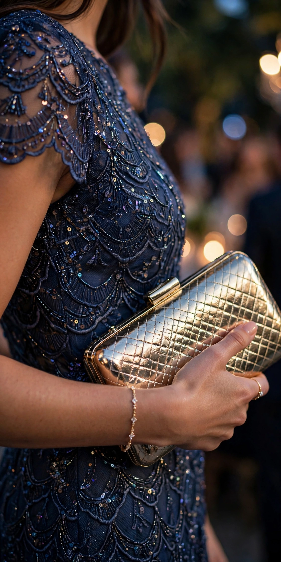 Close-up detail of a navy beaded cocktail dress with a gold clutch and delicate bracelet