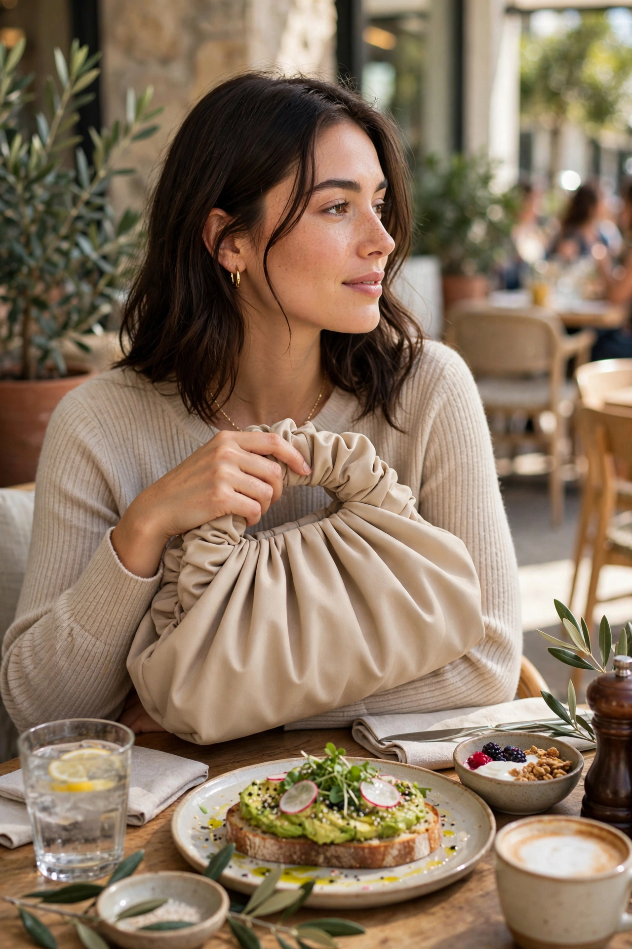Pleated dumpling clutch carried at a bright cafe brunch setting