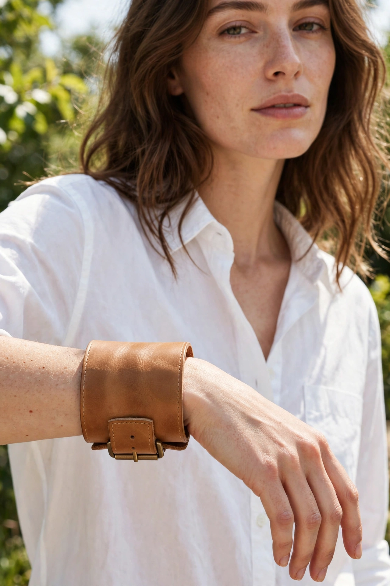 Woman wearing a wide tan leather cuff bracelet with a simple white shirt outfit